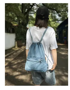 Photo extérieure d'une femme portant un sac à dos en jean bleu avec poche zippée devant
