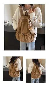 Macro detail of brown nylon backpack showing pleated drawstring pocket and plush charm