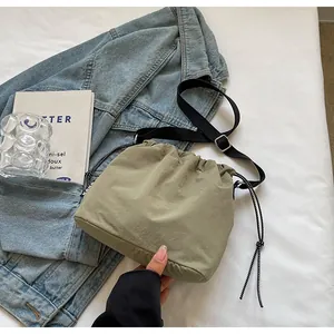 Détail d'un sac seau en nylon olive avec cordon de serrage sur fond de veste en jean