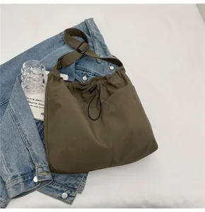 Detail of olive green canvas bucket bag with drawstring closure and large front pockets