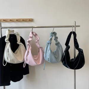 Ruched crescent hobo bags in cream, pink, blue, and black leather displayed in a row