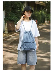 Vue extérieure d'un sac à dos en jean bleu avec cordon de serrage et poche zippée avant