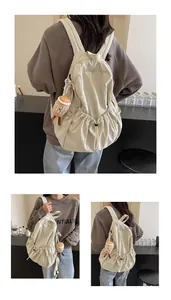 Detail view of cream nylon backpack with pleated texture and cute doll pendant accessory