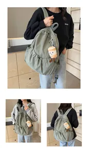 Detail view of avocado green pleated nylon backpack with drawstring and plush charm