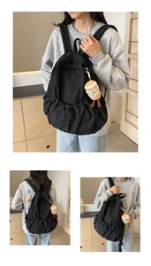 Detail of black pleated nylon backpack featuring drawstring closure and coffee cup plush charm