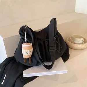 Black canvas drawstring bucket bag with cute plush coffee charm and adjustable strap