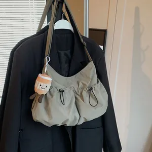 Olive green nylon drawstring crossbody bucket bag with a cute plush coffee cup charm