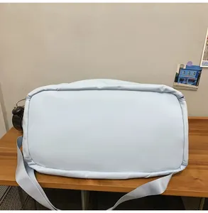 Primer plano del bolso de viaje azul cielo con correa tejida y textura de nailon mate