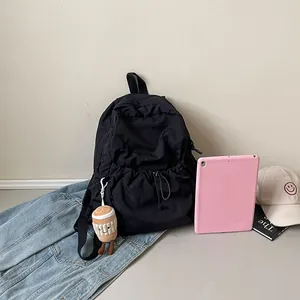 Minimalist black pleated nylon backpack with a drawstring pocket and cute plush charm