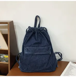 Gros plan détaillé du sac à dos en jean bleu foncé avec cordon sur table en bois