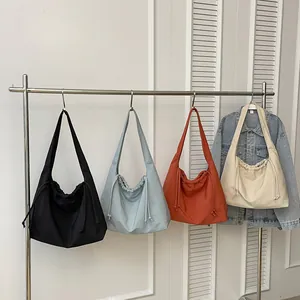 Borse tote in tela con coulisse in vari colori appese su un appendiabiti