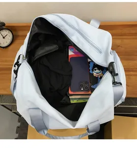 Vista interior del bolso de viaje con ropa, tableta y libros sobre mesa de madera
