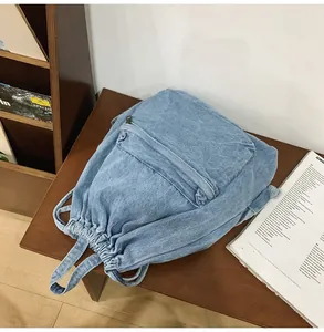Détail du sac à dos en jean bleu clair avec cordon de serrage et poche zippée rétro