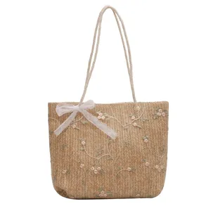 Handgefertigte Strohtasche mit Blumenstickerei und weißer Spitzenschleife für den Sommer