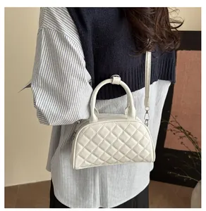 Detail of white quilted crossbody bag with silver hardware and adjustable shoulder strap