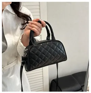 Detail of black quilted faux leather handbag with adjustable strap and diamond stitching
