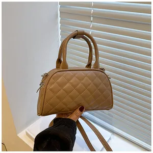 Close-up of caramel brown quilted boston bag with silver hardware and top handle