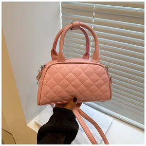 Detailed close-up of a pink quilted Boston bag with stitching and double handles