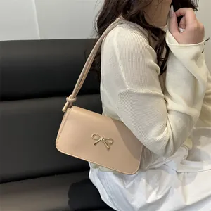 Elegante borsa sottobraccio beige con fibbia a fiocco dorata e tracolla con nodi