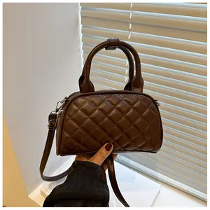 Detail of diamond quilted dark brown Boston bag with sturdy handles and metal zipper