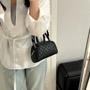 Quilted black Boston handbag with silver hardware and adjustable strap on a model