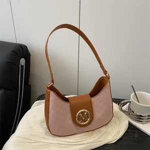 Pink and brown vintage hobo bag with letter print and gold M logo on a white fabric base