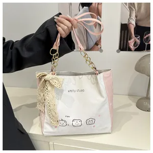 Detail of white canvas tote with pink cat print and lace bow on gold chain strap