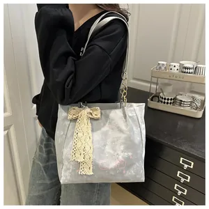 Detail of grey tote bag with lace bow, cartoon print, and golden chain strap detail