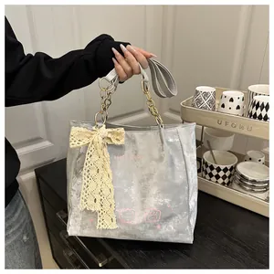 Detail of grey suede tote bag with lace bow charm and cartoon cat print with metal chain strap