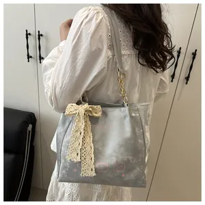 Detail of silver textured tote bag with pink cat print and lace bow accessory