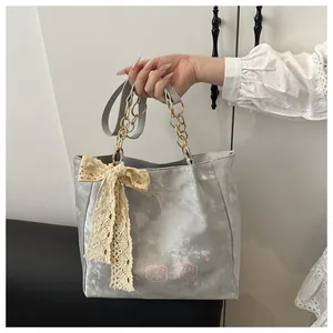 Detail of grey tote bag with pink cartoon print, chain handles and lace bow decoration
