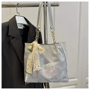 Detail of silver tote bag with pink bear print and elegant lace bow charm accessory