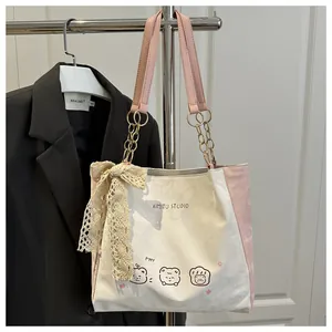 Detail of printed canvas tote bag with pink straps and a large lace bow accent