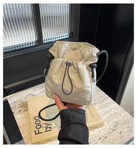 Λεπτομέρεια μπεζ καπιτονέ νάιλον τσάντας bucket με κορδόνι και μαγνητικό κούμπωμα