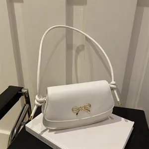 Dettaglio della borsa in pelle bianco crema con chiusura in metallo a fiocco dorato