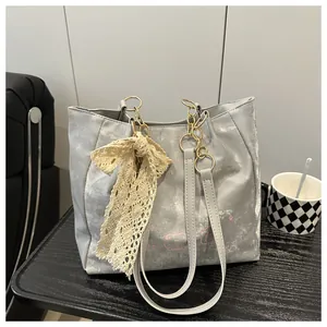 Detail of silver tote bag with lace bow, chain strap and cartoon print on textured table