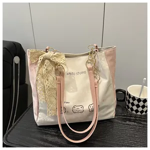 Detail of printed tote bag with lace bow accessory and pink faux leather strap
