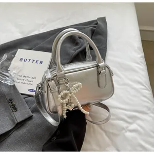 Detail of silver metallic handbag with pleated texture and pearl bow charm accessory