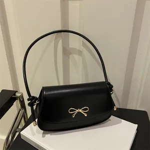 Dettaglio di una borsa a tracolla nera chic con fiocco decorativo in metallo dorato