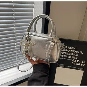 Detail of silver metallic textured handbag featuring a pearl bow charm and metal handle