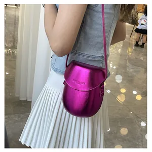 Detail of metallic pink saddle bag with smooth leather texture and crossbody strap