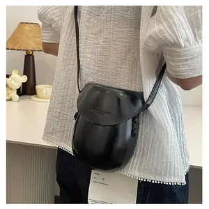 Detail of minimalist black saddle bag with FASHION & BAGS embossed lettering and PU finish