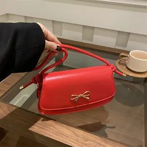 Dettaglio ravvicinato della borsa rossa con fibbia dorata a fiocco e tracolla