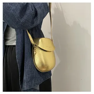 Detail shot of a mini golden saddle bag featuring a smooth metallic finish and slim strap