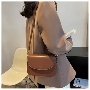 Brown leather saddle shoulder bag showing texture and branding in a lifestyle setting