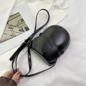 Minimalist black saddle crossbody bag in glossy faux leather with adjustable strap