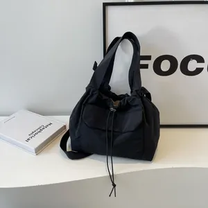 Sac seau minimaliste en nylon noir avec cordon de serrage, poche avant et poignée
