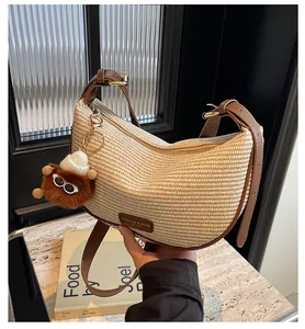 Détail du sac croissant tissé avec bandoulière en cuir brun et breloque ours mignon