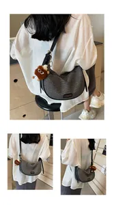 Détail du sac demi-lune tressé gris foncé avec bandoulière et pendentif en peluche