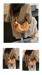Détail du sac croissant tissé avec charm lion en peluche et bandoulière en cuir